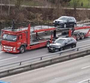 Автовоз із легковими автомобілями на трасі
