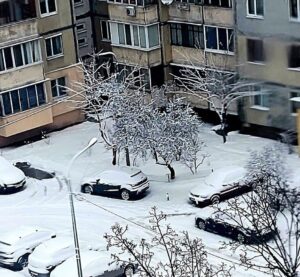Засніжені автомобілі у дворі київської багатоповерхівки після снігопаду